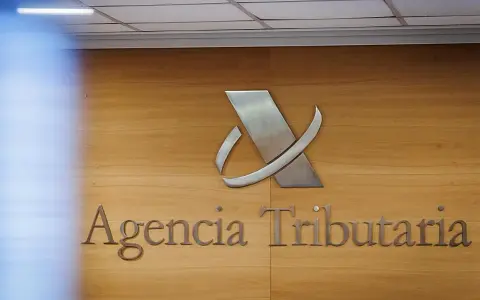 Logo y nombre de la Agencia Tributaria en una pared de madera.