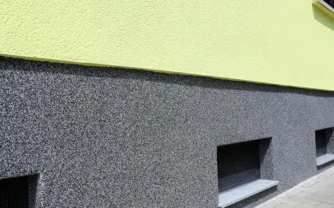 Der Sockel ist mit einem robusten, grauen Körnchenputz verputzt, der gut zu den kleinen Kellerfenstern passt.