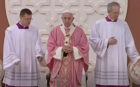 Pope Francis, in a pink vestment for the fourth Sunday of Lent, stands between two clergy members in white albs.