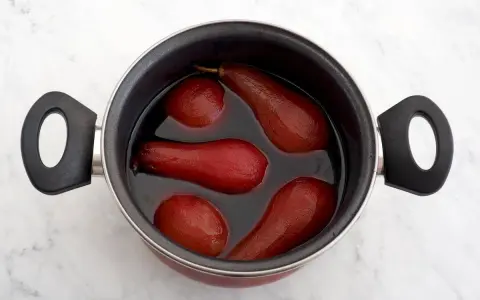 Olla con peras al vino tintas, listas para ser un postre delicioso.