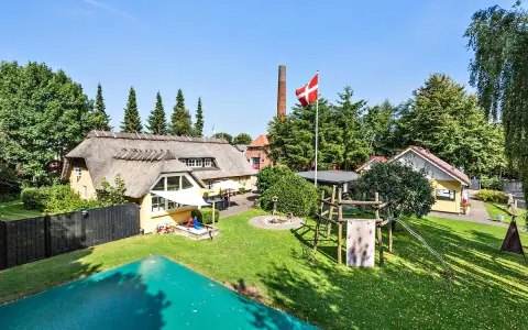 En idyllisk campingplats i Billund med halmtak, lekplats och danska flaggan vajande stolt.