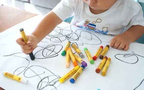 Bambino disegna con pastelli su foglio bianco. I disegni dei bambini sono un modo per esprimere emozioni, ma quando preoccuparsi?