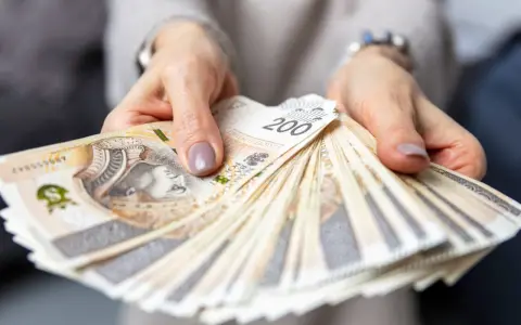 Dłonie trzymające plik banknotów 200 zł. Pytanie o to, ile zarabia hotelarz, często wiąże się z takimi widokami.