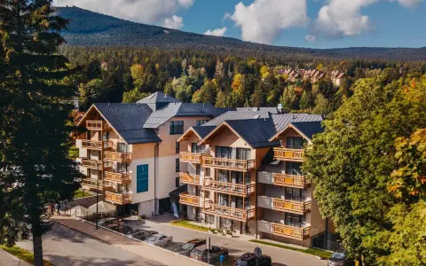 Nowoczesny hotel z drewnianymi balkonami w otoczeniu jesiennego lasu. Idealne noclegi Szklarska Poręba dla miłośników gór.