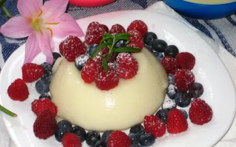 Panna cotta z malinami i borówkami, posypana cukrem pudrem. Idealny legumina przepis na deser.