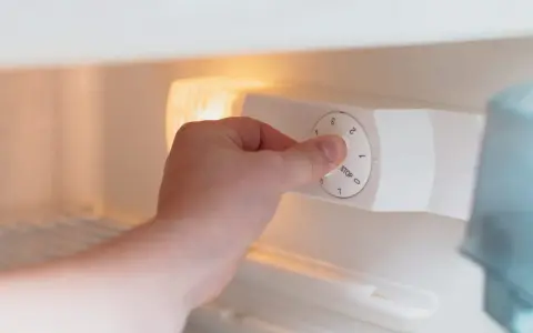 Main tenant ajuste la molette pour régler la quelle temperature congelateur. Le bouton indique "STOP" et des chiffres de 0 à 7.