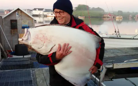 Szczęśliwy wędkarz z ogromnym halibutem. Taka zanęta halibut na jakie ryby? Na rekordowe!