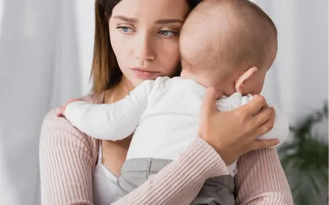 Traurige Mutter hält ihr Baby. Ihre Augen spiegeln eine tiefe Enttäuschung wider, vielleicht gender disappointment.