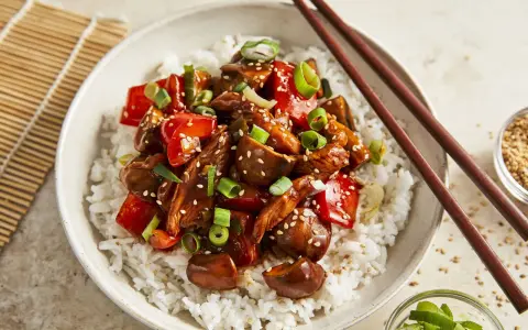 Schüssel mit Reis und einem köstlichen Chicken Teriyaki, garniert mit Frühlingszwiebeln und Sesam.
