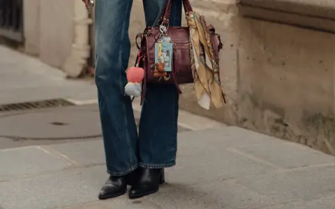 Botas negras elegantes con tacón, perfectas para complementar unos pantalones vaqueros anchos y un bolso de cuero con adornos.