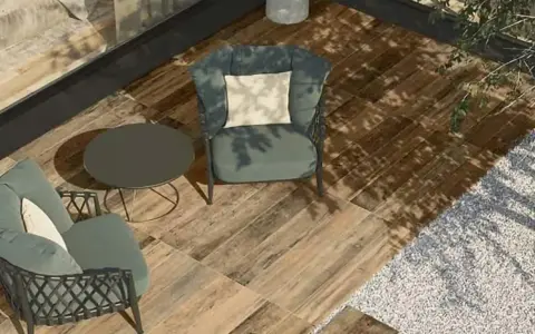 Aménager une terrasse moderne avec des fauteuils confortables, une table basse et un sol imitation bois. L'ombre des arbres crée une atmosphère paisible.