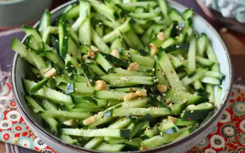 Una fresca insalata di cetrioli tagliati a julienne, condita con semi di sesamo, arachidi e peperoncino.