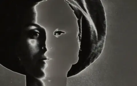 Volto femminile in profilo, un'icona di stile di Lillian Bassman, con un gioco di luci e ombre che ne esalta la misteriosa bellezza.