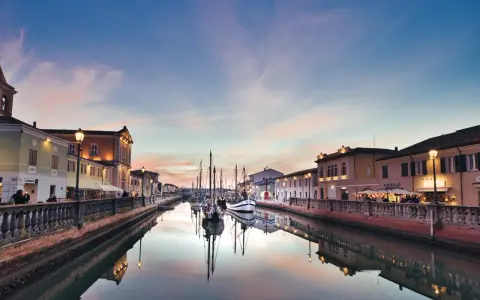 Canale di Cesenatico al tramonto, con barche a vela ormeggiate e riflessi sull'acqua. La riviera cesenatico incanta con i suoi colori.