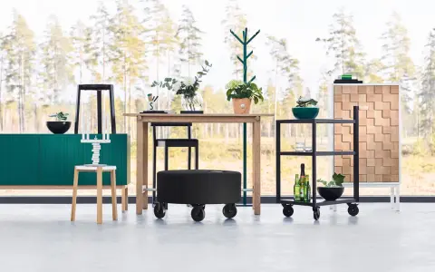 Inredning med en grön skänk, träbord, svarta pallar och en rullvagn. Design från a2 designers.