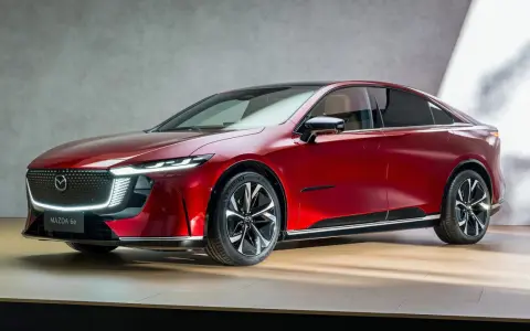 Elegancka, czerwona mazda elektryczna z nowoczesnym designem, prezentowana na drewnianej scenie.