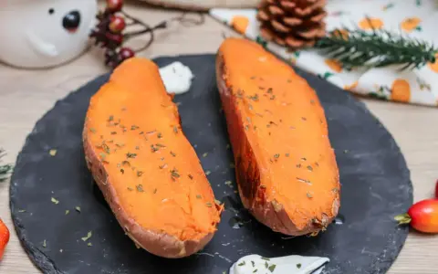 Dos mitades de boniato al horno, tiernas y doradas, con hierbas picadas y una cucharada de crema.