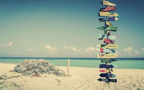 Strand mit Schildern zu fernen Zielen. Ein Traum für ein **auslandsjahr kostenlos**?