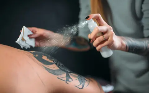Artysta spryskuje skórę klienta, przygotowując ją do dalszej pracy. Dobre pytanie, jakie mydło do tatuażu wybrać, by zapewnić najlepsze efekty i higienę.