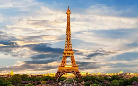 Le symbole de la Tour Eiffel se dresse fièrement sous un ciel nuageux, illuminé par les rayons du soleil couchant.