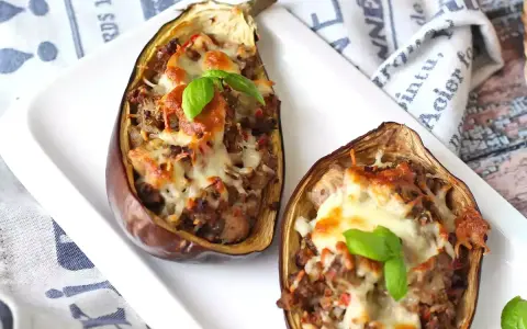Melanzane ripiene al forno velocissime, con un saporito ripieno e formaggio filante, guarnite con basilico fresco.