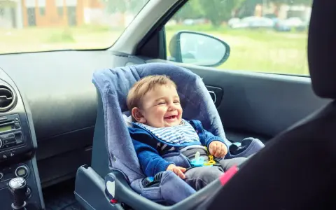 Bebé feliz en silla de coche, asiento delantero, listo para la aventura.