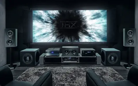 Installation home cinema avec écran THX, amplificateur, enceintes et fauteuils en cuir noir pour une expérience immersive.