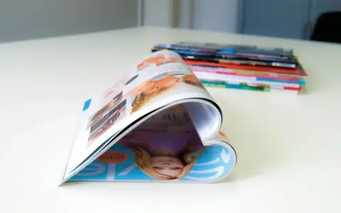 Ein aufgeschlagenes Magazin, das wie ein Herz geformt ist, liegt auf einem Tisch. Im Hintergrund stapeln sich weitere Ausgaben der aero zeitschrift.