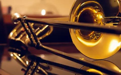 Błyszczące, złote puzony, różne rodzaje instrumentów dętych blaszanych, odbijające się w lustrzanej powierzchni.
