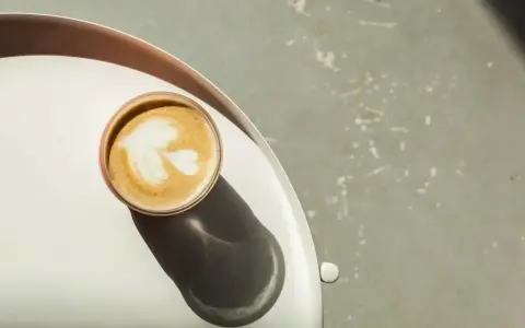 Idealna kawa flat white z pianką w kształcie liścia, podana na tacy.