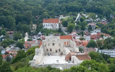 Ruiny zamku w Kazimierzu Dolnym na tle zielonych wzgórz i zabudowań.