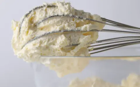 Puszysty krem z mascarpone, ubijany na drucianych trzepaczkach miksera, gotowy do deseru.