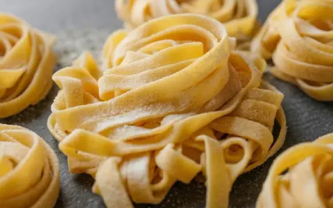 Nidi di tagliatelle fatte in casa, spolverate di farina, pronte per essere cucinate.