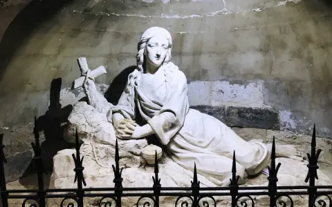 Sculpture of Mary Magdalene in repose, near a cross, possibly at her burial site.