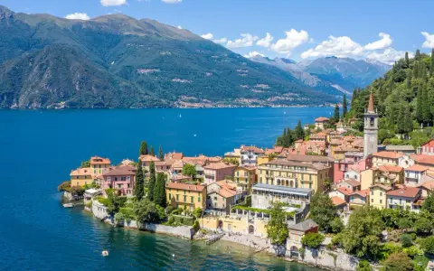 Färgstarka hus vid en azurblå sjö, omgivna av gröna berg. Ett perfekt exempel på mysiga resmål i Italien.
