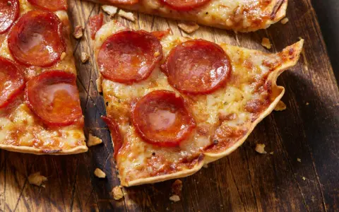 Pyszna pizza na tortilli z pepperoni, roztopionym serem i chrupiącym spodem, podana na drewnianej desce.