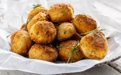 Un mucchio invitante di polpette in bianco, dorate e croccanti, guarnite con rosmarino fresco e sale grosso.