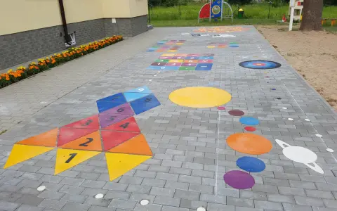 Kolorowe gry plenerowe na placu zabaw: rakieta z liczbami, układ planet i plansza do gry.