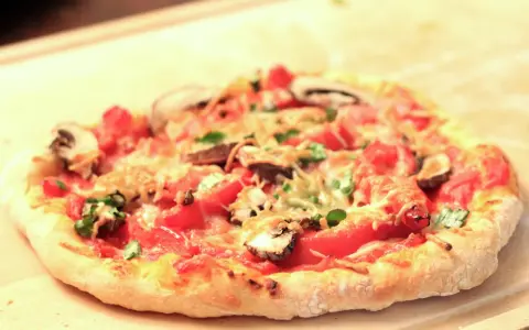 Eine köstliche Pizza mit Pilzen und Tomaten auf einem luftigen pizzateig mit lievito madre, bereit zum Genießen.
