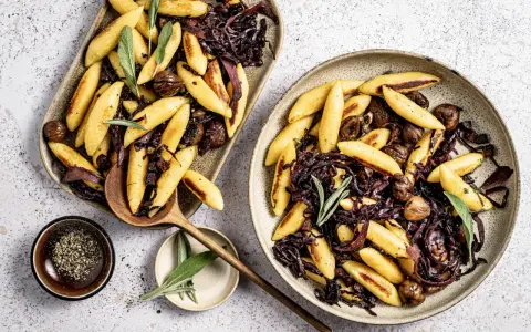 Schupfnudeln mit Rotkohl und Kastanien, garniert mit Salbei. Ein herzhaftes Gericht, das zum Genießen einlädt.