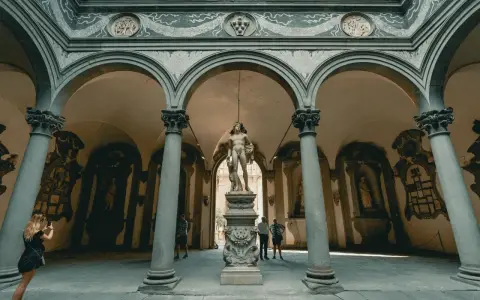 Cour intérieure de Florence avec une statue antique au centre. Une femme prend une photo de la statue florence.