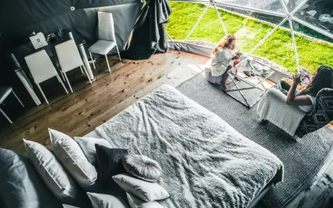 Dwie kobiety relaksują się w luksusowym namiocie. Przytulne wnętrze z wygodnym łóżkiem i stolikiem kawowym, idealne na camping w Zakopanem.