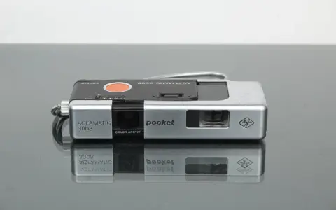 Srebrny aparat Agfamatic 3008 z napisem "pocket" i logo Agfa. Idealny do uchwycenia wspomnień.
