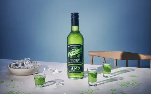 O.P. Anderson Gunpowder i gröna shotglas på ett bord med is och tic-tac-toe-ritningar.
