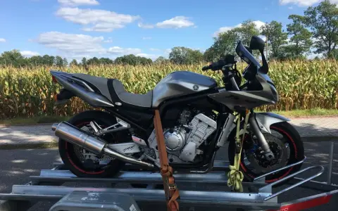 Srebrny motocykl na przyczepce, gotowy do transportu. Może to być związane z akcyzą na motocykle, która wpływa na koszty zakupu.