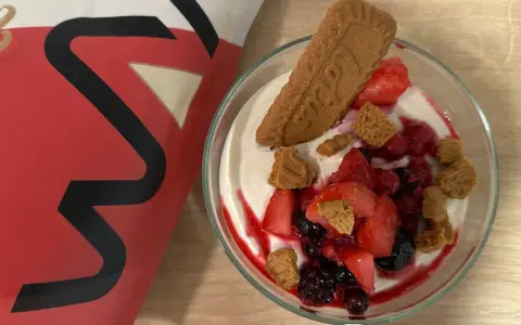 Leckere vegane Smoothie Bowl mit frischen Beeren, Kekskrümeln und einem Lotus-Keks.