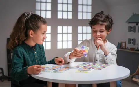 Deux enfants jouent à un jeu de cartes coloré, une belle illustration d'activités sans écran pour adultes et enfants.