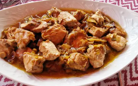 Sabroso bonito en escabeche, trozos de pescado tierno con cebolla en una salsa dorada.