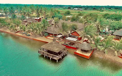 Rajskie wakacje w Ghanie: tropikalny kurort z palmami, plażą i domkami na wodzie.