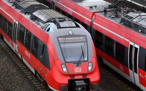 Zwei rote Regio-Züge der Deutschen Bahn stehen nebeneinander auf den Gleisen.